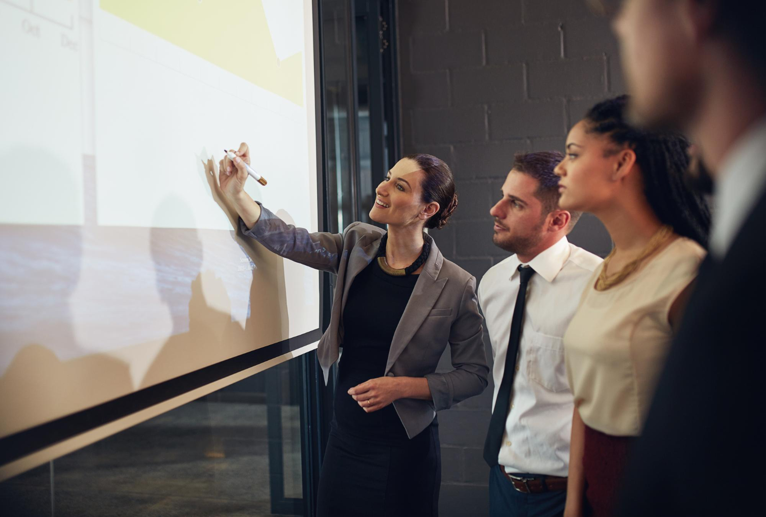 Woman drawing on white board with co-workers