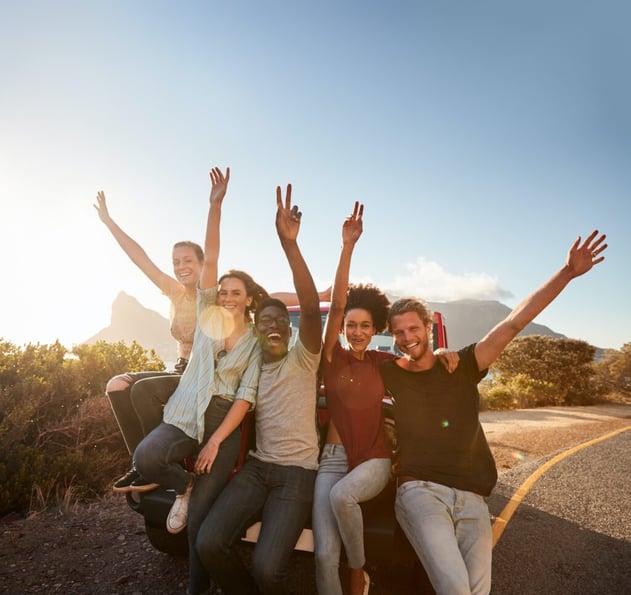 five-millennial-friends-on-a-road-trip-taking-a-break-leaning-on-the-car-waving-to-camera-1024x966